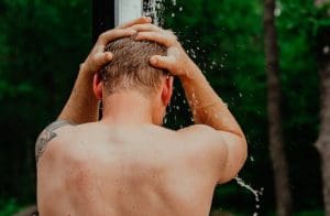 This shows a man showering in cold water after a sauna. We cover the benefits of cold water plunging after having a sauna in the sauna blog